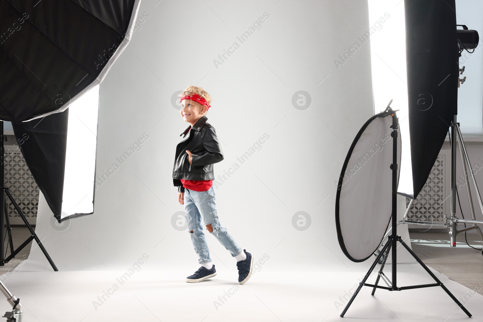 Photo of Little boy on light grey background in photo studio with professional equipment