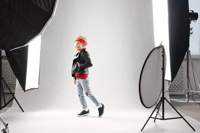 Photo of Little boy on light grey background in photo studio with professional equipment