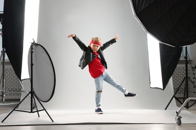 Photo of Little boy on light grey background in photo studio with professional equipment
