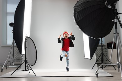 Photo of Little boy on light grey background in photo studio with professional equipment