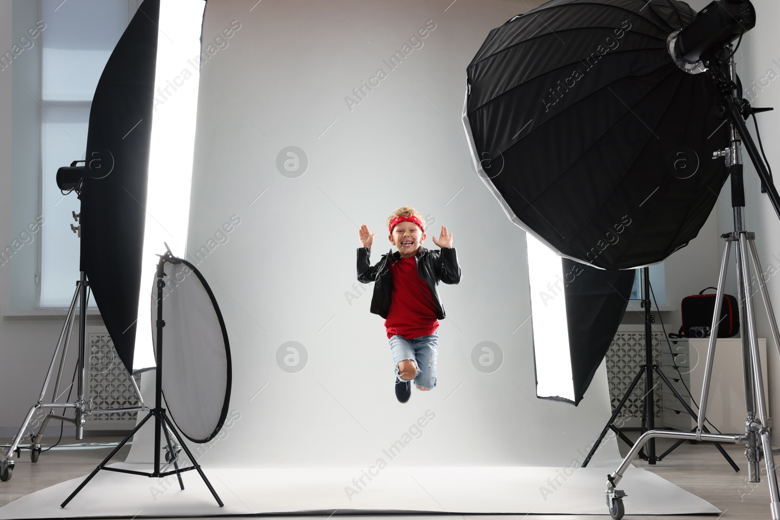 Photo of Little boy on light grey background in photo studio with professional equipment
