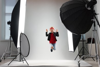 Photo of Little boy on light grey background in photo studio with professional equipment