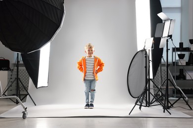 Photo of Little boy on light grey background in photo studio with professional equipment