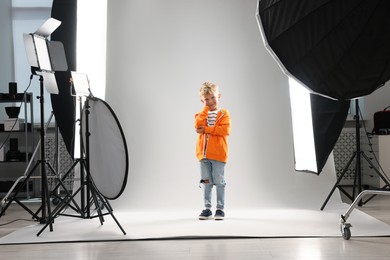 Photo of Little boy on light grey background in photo studio with professional equipment