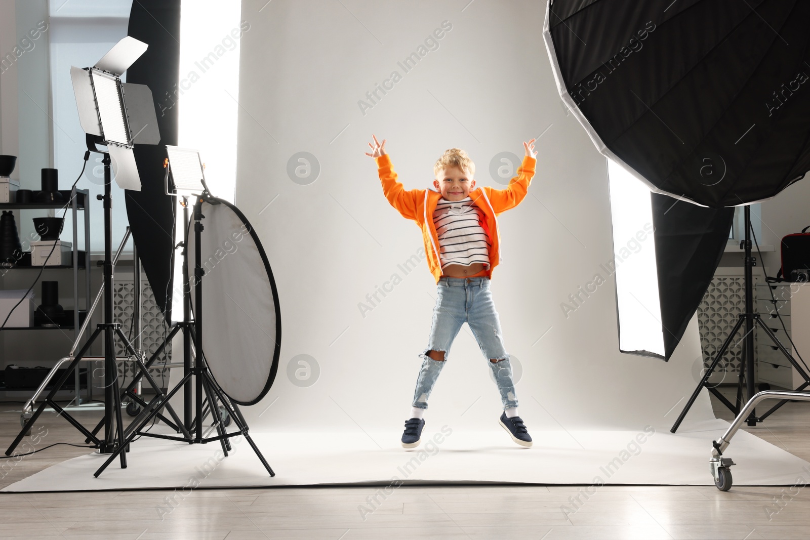 Little boy on light grey background in photo studio with professional equipment Photo of Little boy on light grey background in photo studio with professional equipment