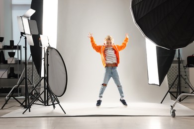 Photo of Little boy on light grey background in photo studio with professional equipment
