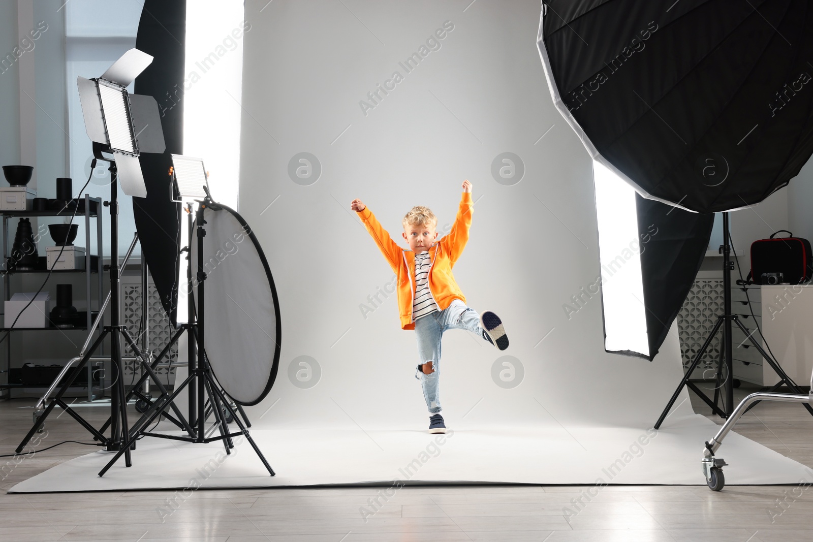 Little boy on light grey background in photo studio with professional equipment Photo of Little boy on light grey background in photo studio with professional equipment
