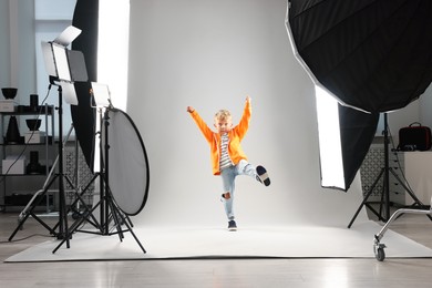 Photo of Little boy on light grey background in photo studio with professional equipment