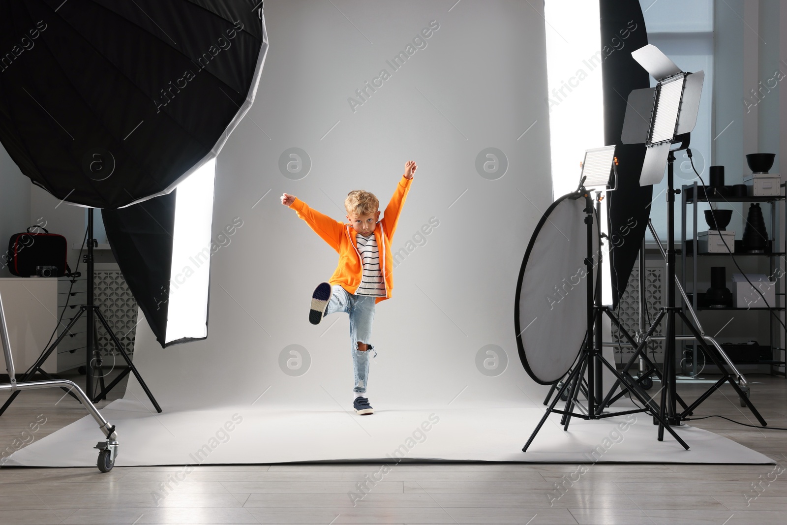 Little boy on light grey background in photo studio with professional equipment Photo of Little boy on light grey background in photo studio with professional equipment