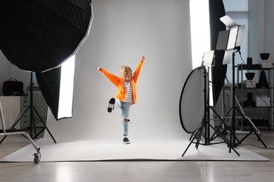 Photo of Little boy on light grey background in photo studio with professional equipment