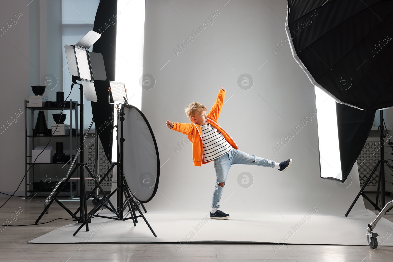 Photo of Little boy on light grey background in photo studio with professional equipment