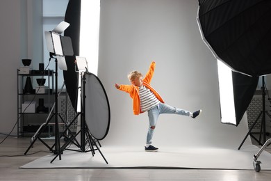Photo of Little boy on light grey background in photo studio with professional equipment
