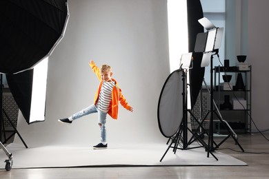 Photo of Little boy on light grey background in photo studio with professional equipment