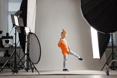 Photo of Little boy on light grey background in photo studio with professional equipment