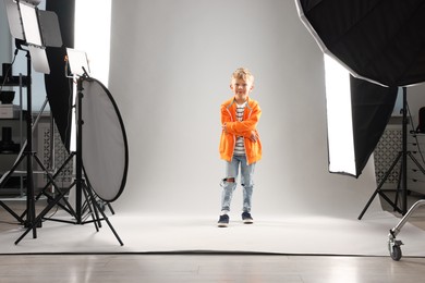 Photo of Little boy on light grey background in photo studio with professional equipment
