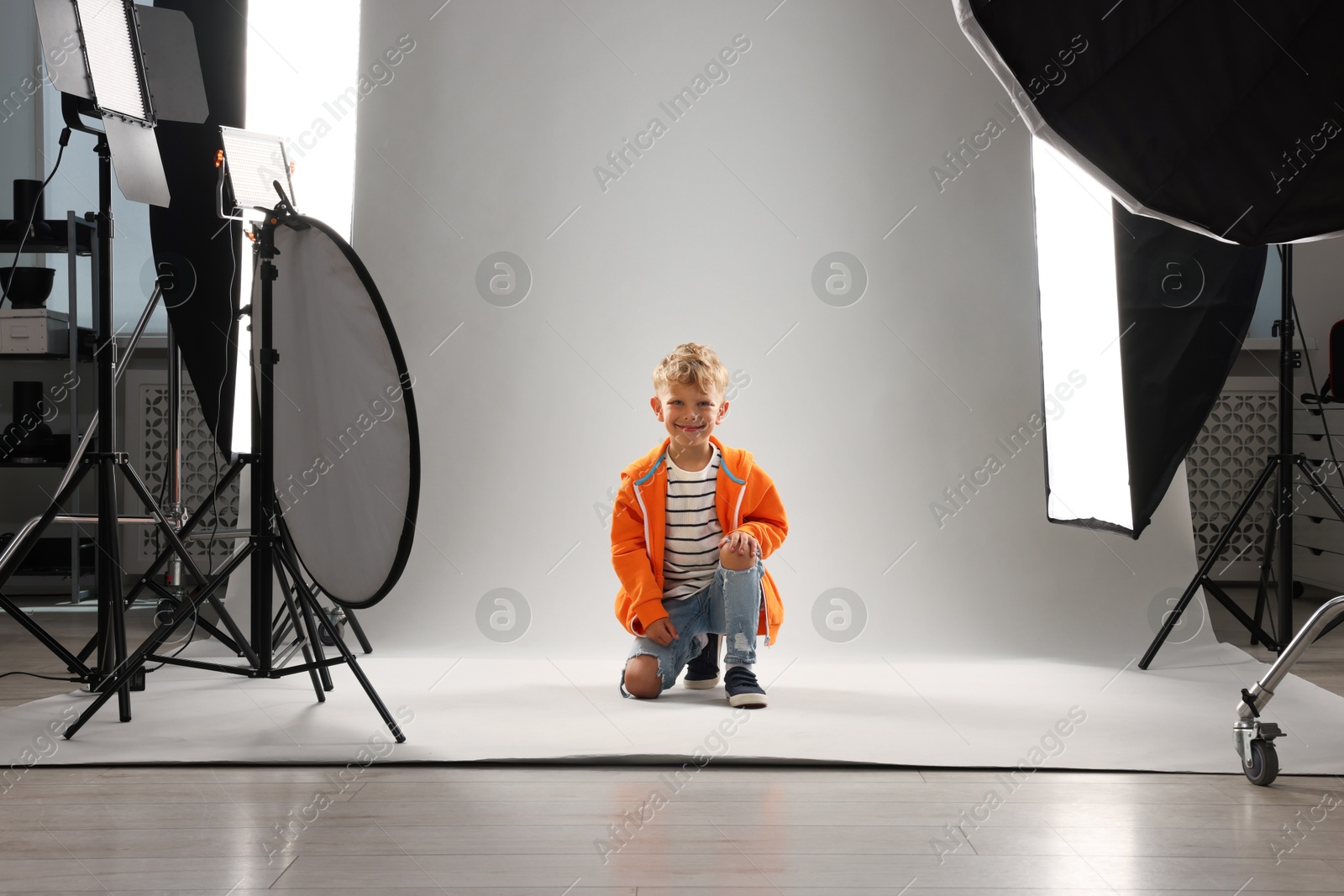Photo of Little boy on light grey background in photo studio with professional equipment