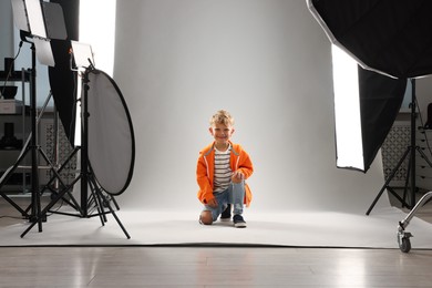 Photo of Little boy on light grey background in photo studio with professional equipment