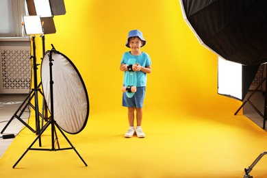 Photo of Little boy with penny board on yellow background in photo studio with professional equipment