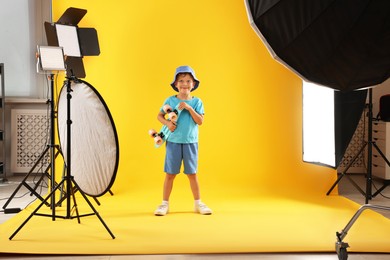 Photo of Little boy with penny board on yellow background in photo studio with professional equipment