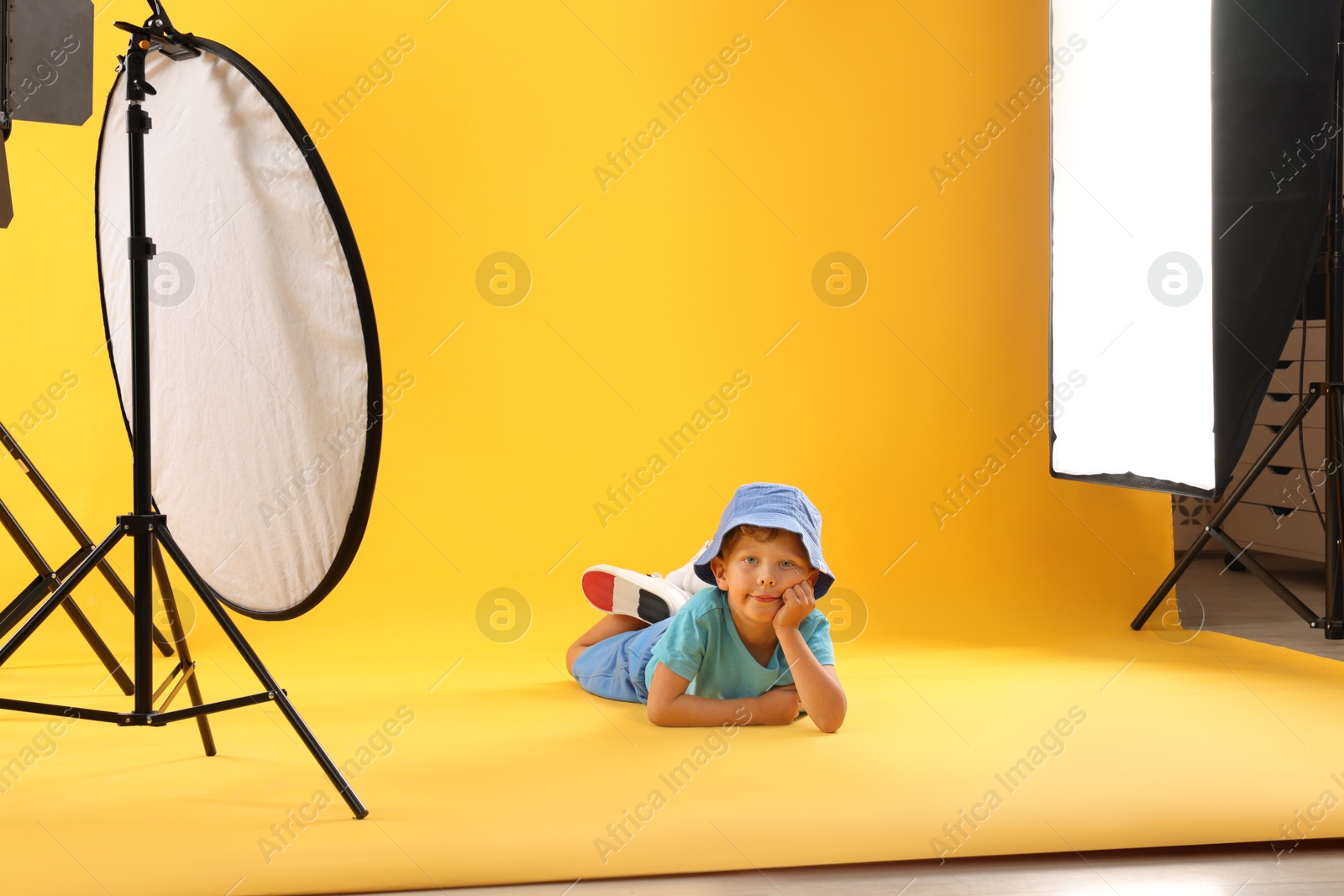 Photo of Little boy on yellow background in photo studio with professional equipment