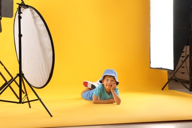 Photo of Little boy on yellow background in photo studio with professional equipment