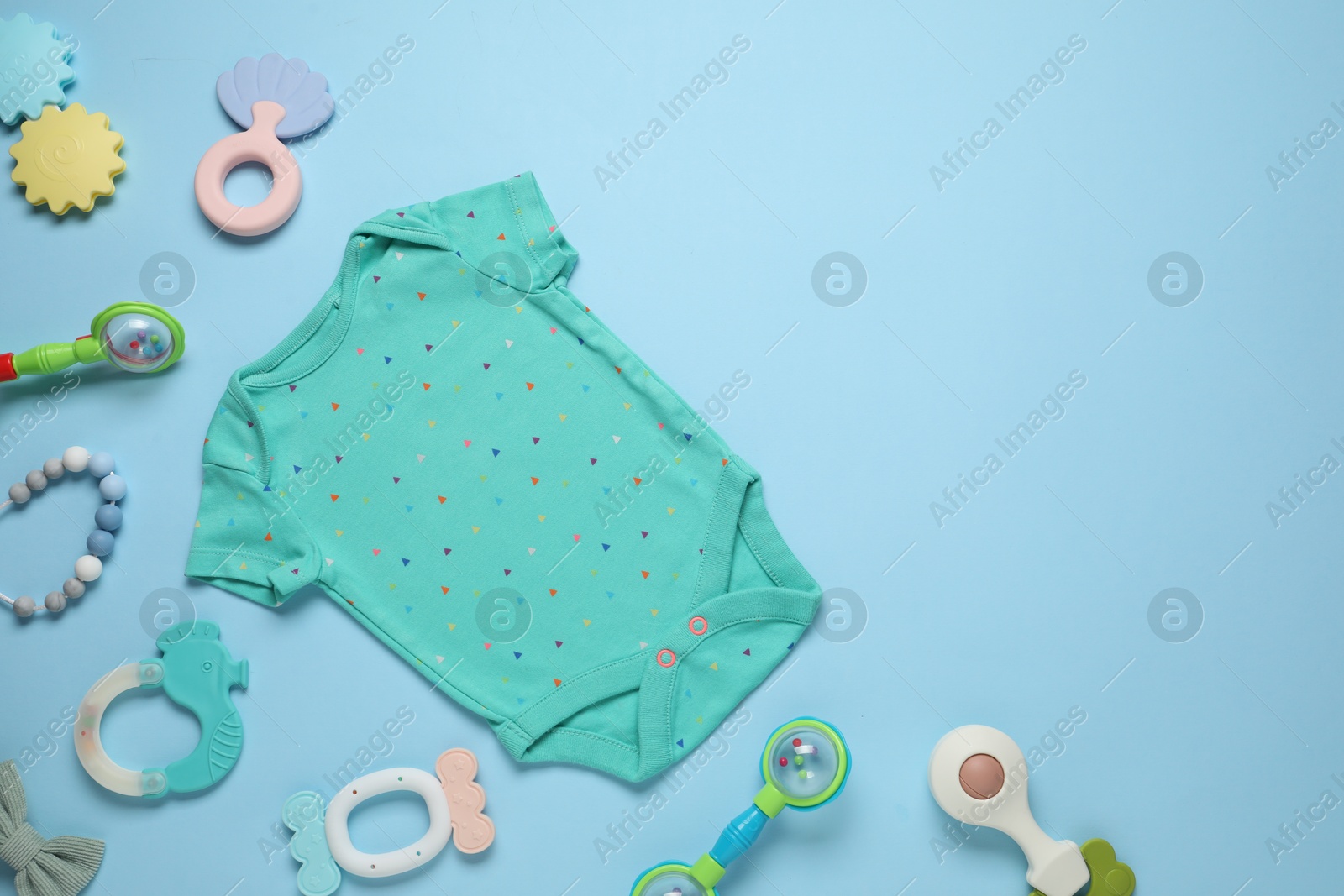 Photo of Baby onesie and accessories on light blue background, flat lay. Space for text