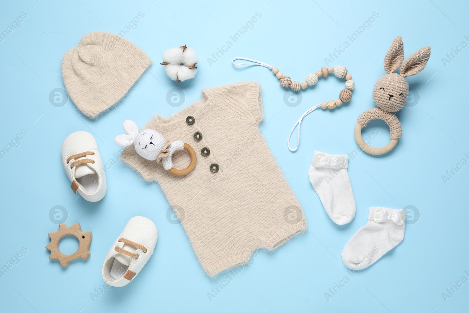 Photo of Cute baby clothes and accessories on light blue background, flat lay