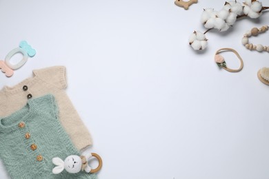 Photo of Cute baby clothes, accessories and cotton flowers on white background, flat lay. Space for text