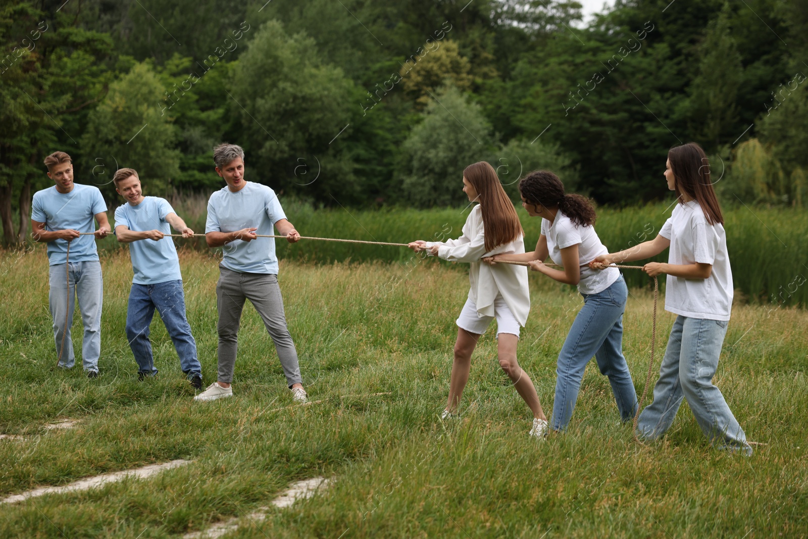 Team building. Group of happy people playing tug of war with rope outdoors Photo of Team building. Group of happy people playing tug of war with rope outdoors