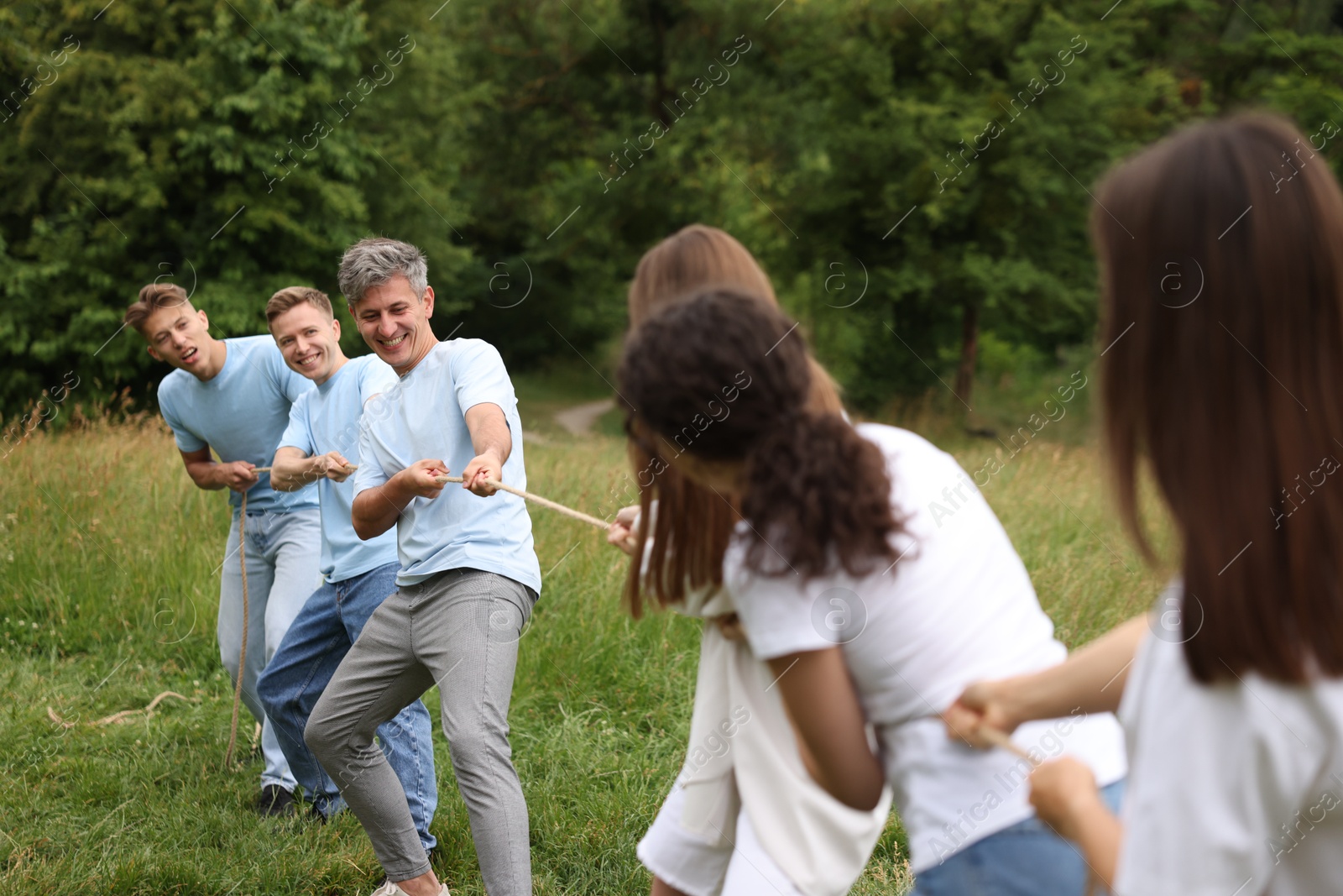 Team building. Group of happy people playing tug of war with rope outdoors Photo of Team building. Group of happy people playing tug of war with rope outdoors
