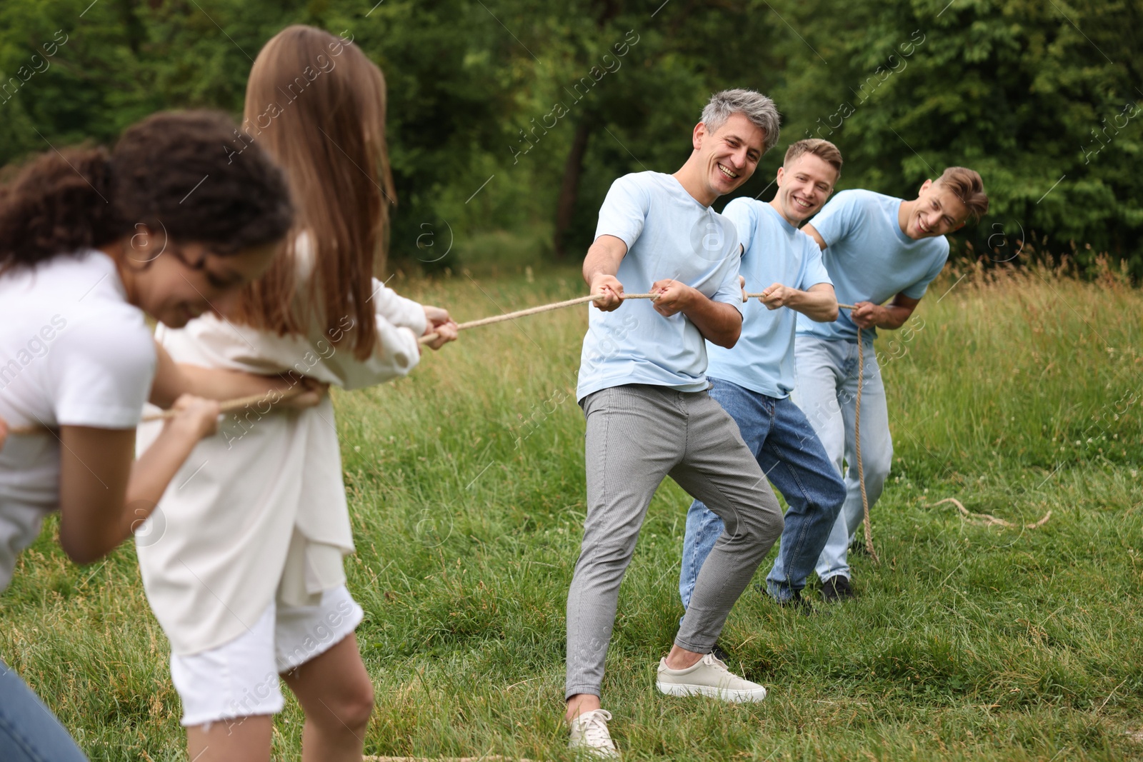 Team building. Group of happy people playing tug of war with rope outdoors Photo of Team building. Group of happy people playing tug of war with rope outdoors
