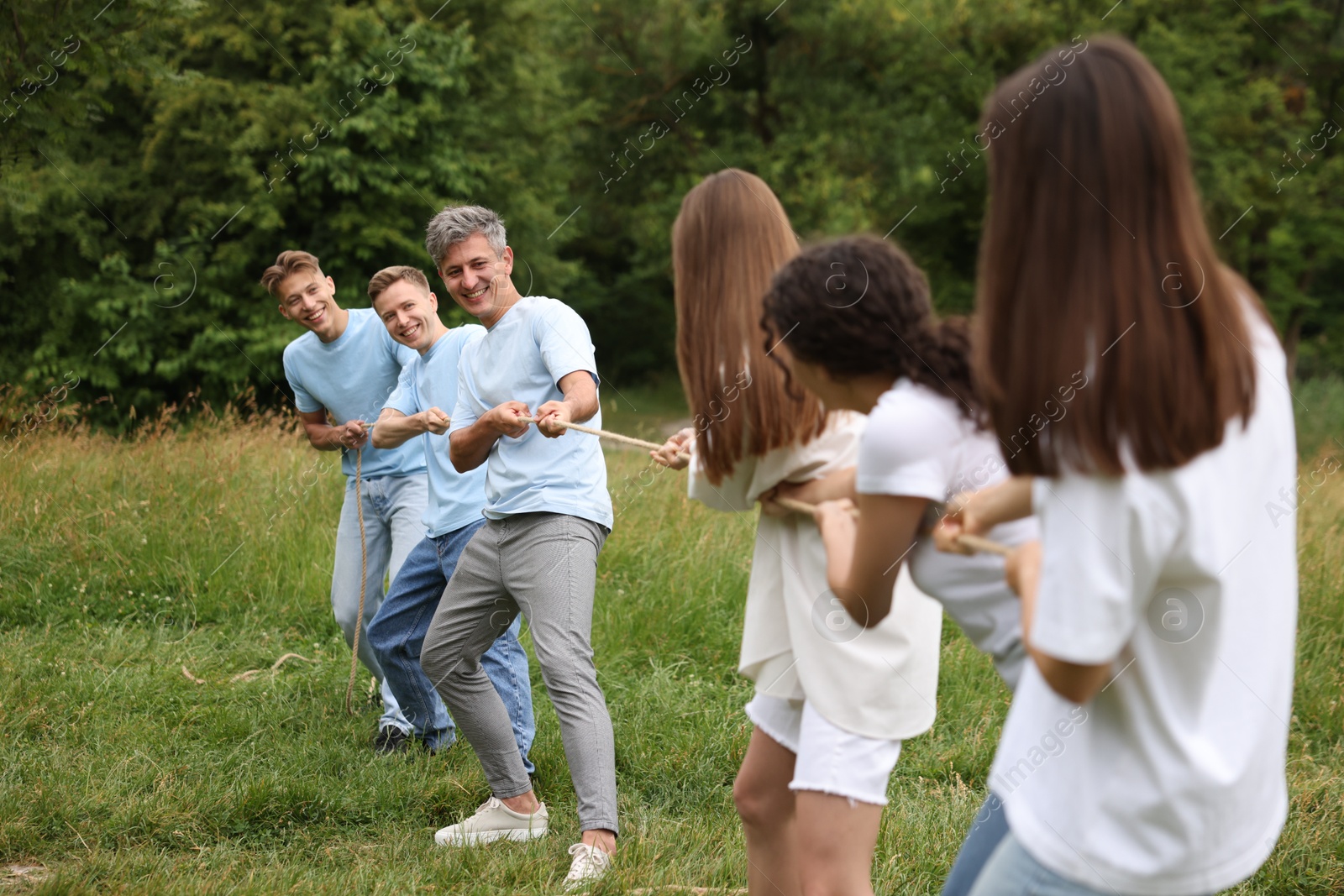 Team building. Group of happy people playing tug of war with rope outdoors Photo of Team building. Group of happy people playing tug of war with rope outdoors
