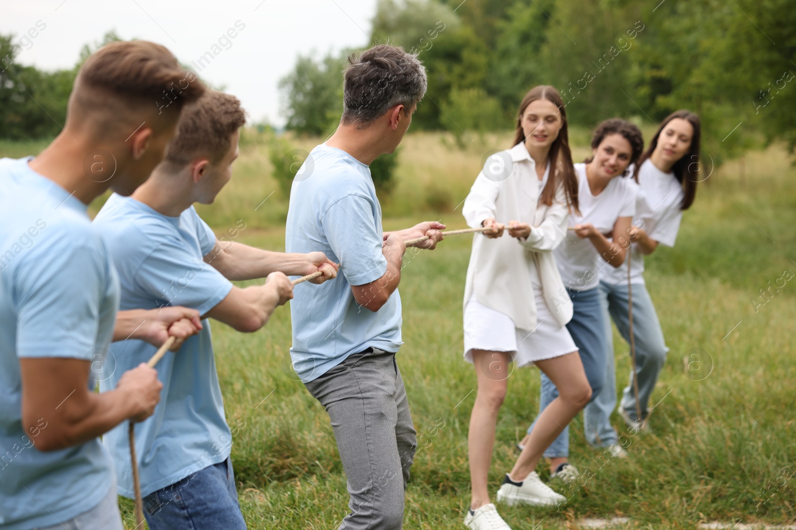 Team building. Group of happy people playing tug of war with rope outdoors Photo of Team building. Group of happy people playing tug of war with rope outdoors