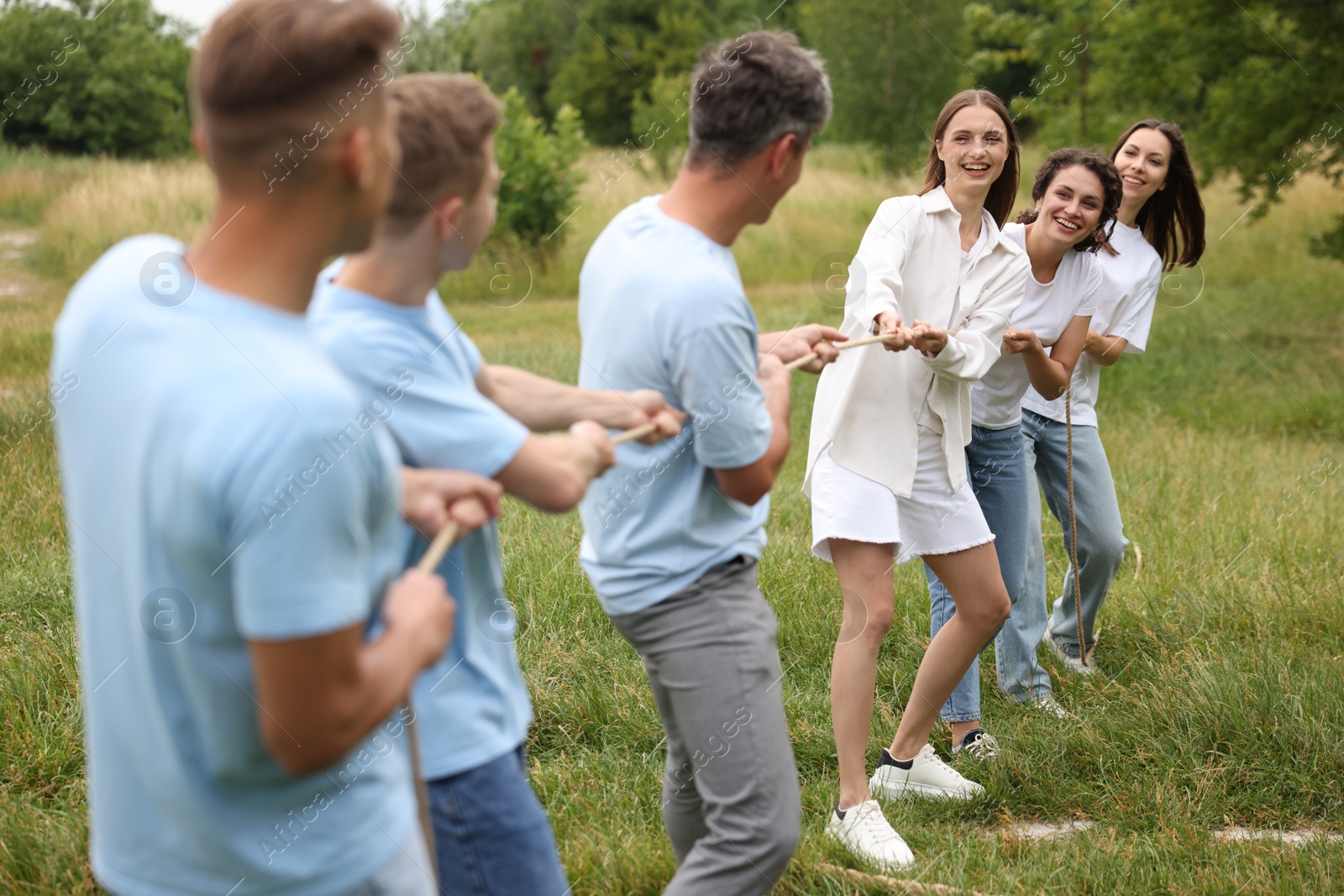 Team building. Group of happy people playing tug of war with rope outdoors Photo of Team building. Group of happy people playing tug of war with rope outdoors