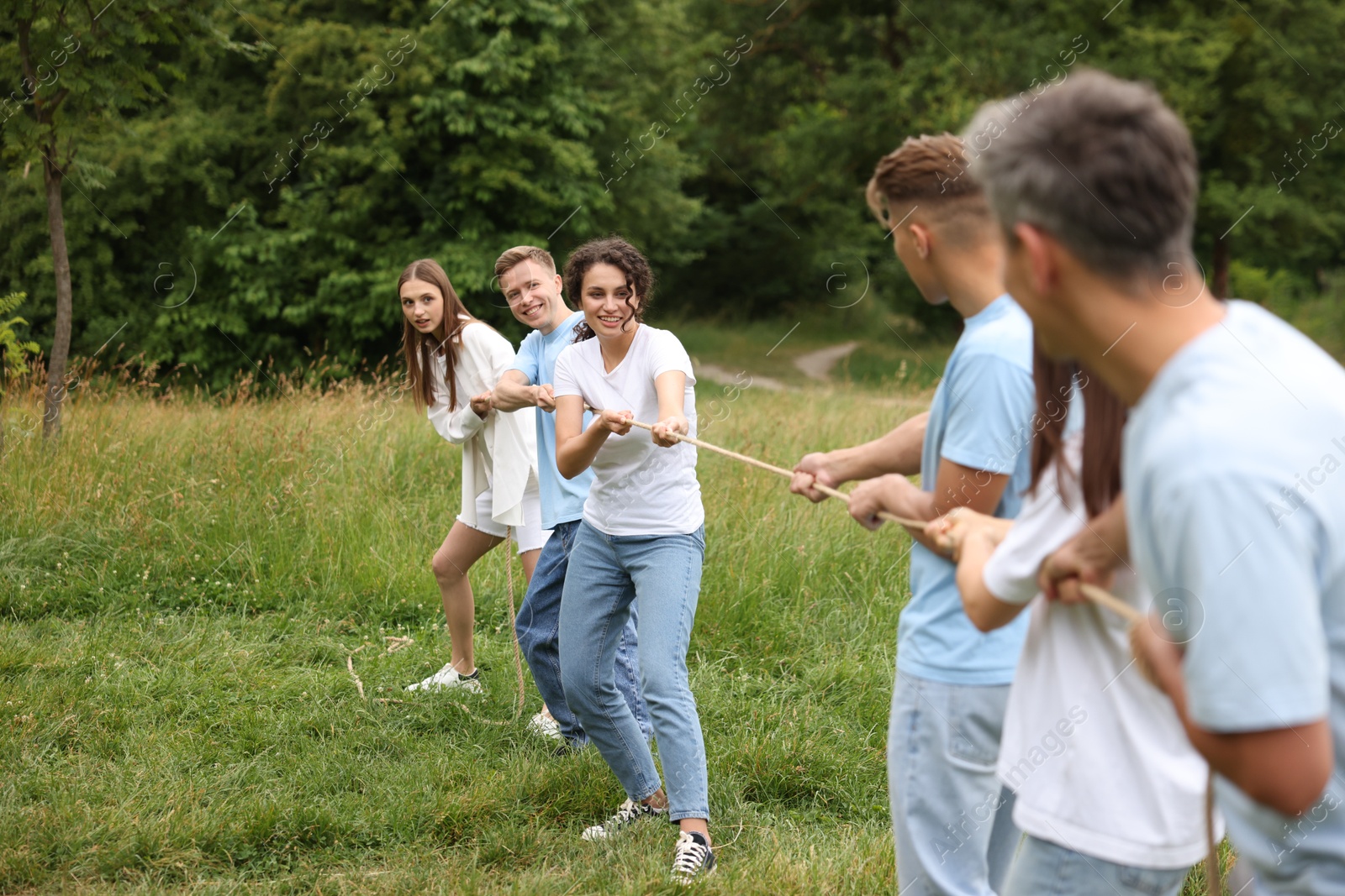 Team building. Group of happy people playing tug of war with rope outdoors Photo of Team building. Group of happy people playing tug of war with rope outdoors