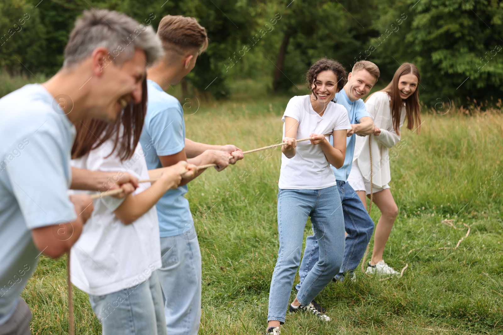Team building. Group of happy people playing tug of war with rope outdoors Photo of Team building. Group of happy people playing tug of war with rope outdoors