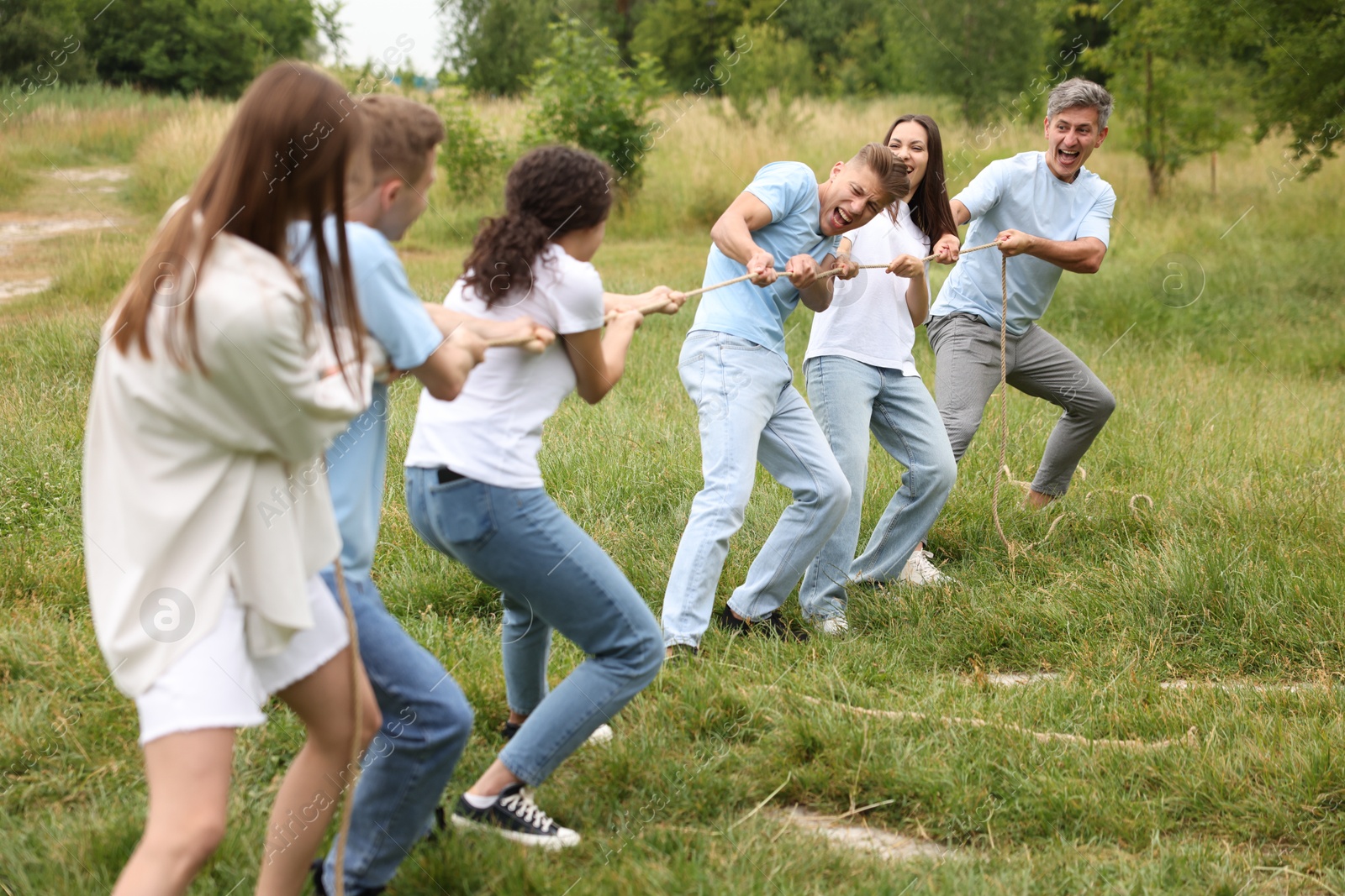 Team building. Group of happy people playing tug of war with rope outdoors Photo of Team building. Group of happy people playing tug of war with rope outdoors