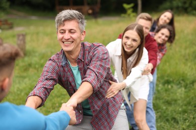 Photo of Team building. Group of happy people holding hands outdoors