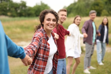 Photo of Team building. Group of happy people holding hands outdoors, selective focus