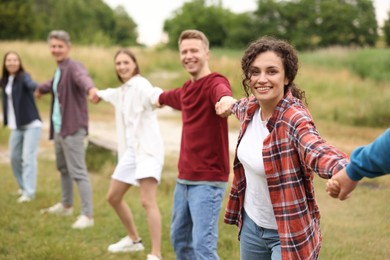 Photo of Team building. Group of happy people holding hands outdoors, selective focus