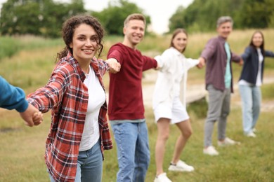 Photo of Team building. Group of happy people holding hands outdoors, selective focus