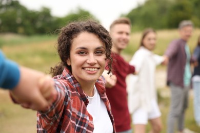 Photo of Team building. Group of happy people holding hands outdoors, selective focus