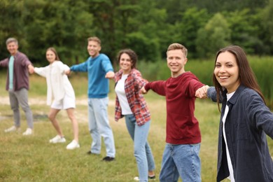 Photo of Team building. Group of happy people holding hands outdoors, selective focus
