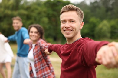 Photo of Team building. Group of happy people holding hands outdoors, selective focus