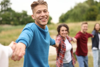 Photo of Team building. Group of happy people holding hands outdoors, selective focus