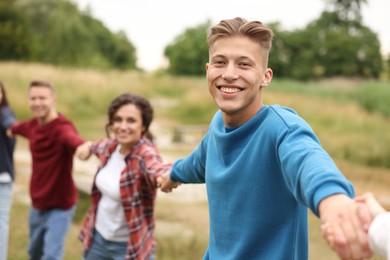 Photo of Team building. Group of happy people holding hands outdoors, selective focus