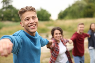 Photo of Team building. Group of happy people holding hands outdoors, selective focus