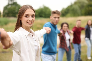 Photo of Team building. Group of happy people holding hands outdoors, selective focus
