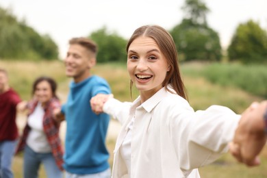 Photo of Team building. Group of happy people holding hands outdoors, selective focus