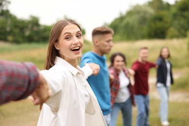 Photo of Team building. Group of happy people holding hands outdoors, selective focus